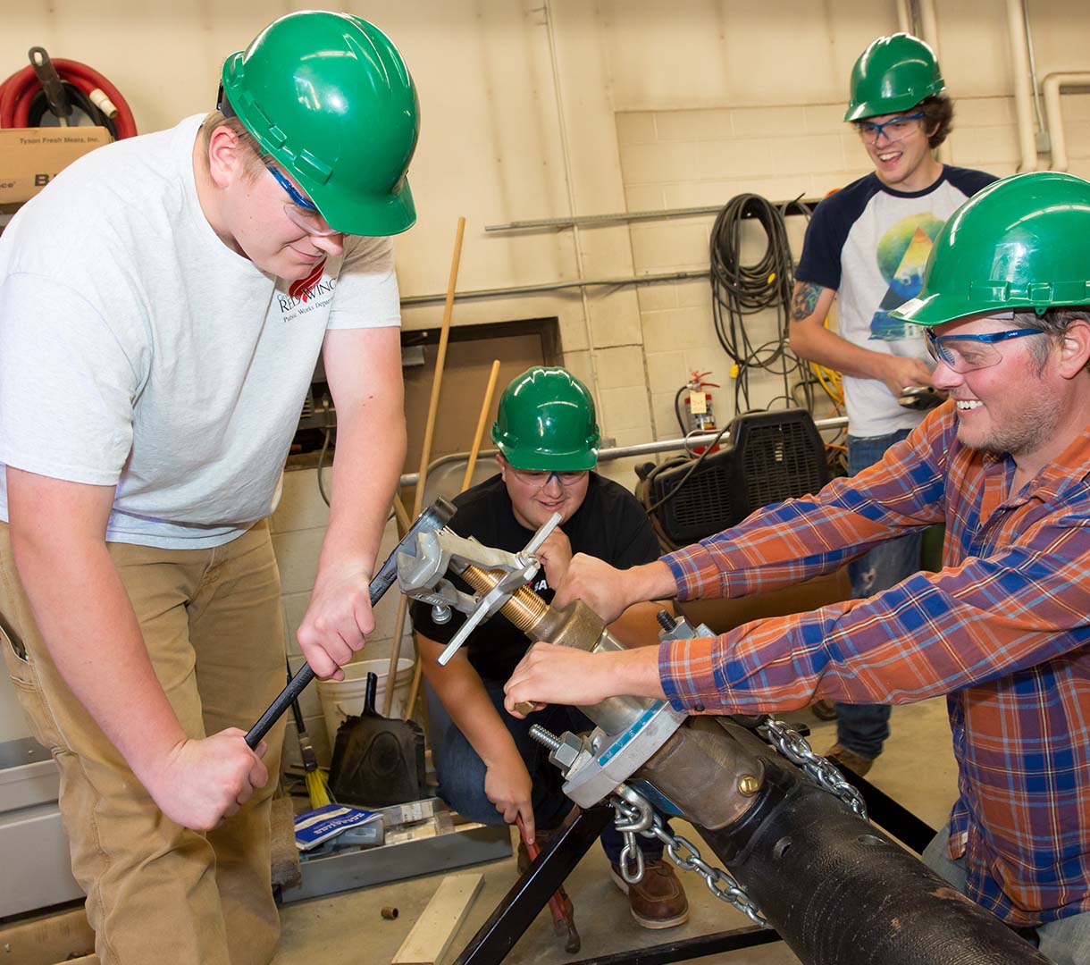 Four male students in hardhats working with power tools