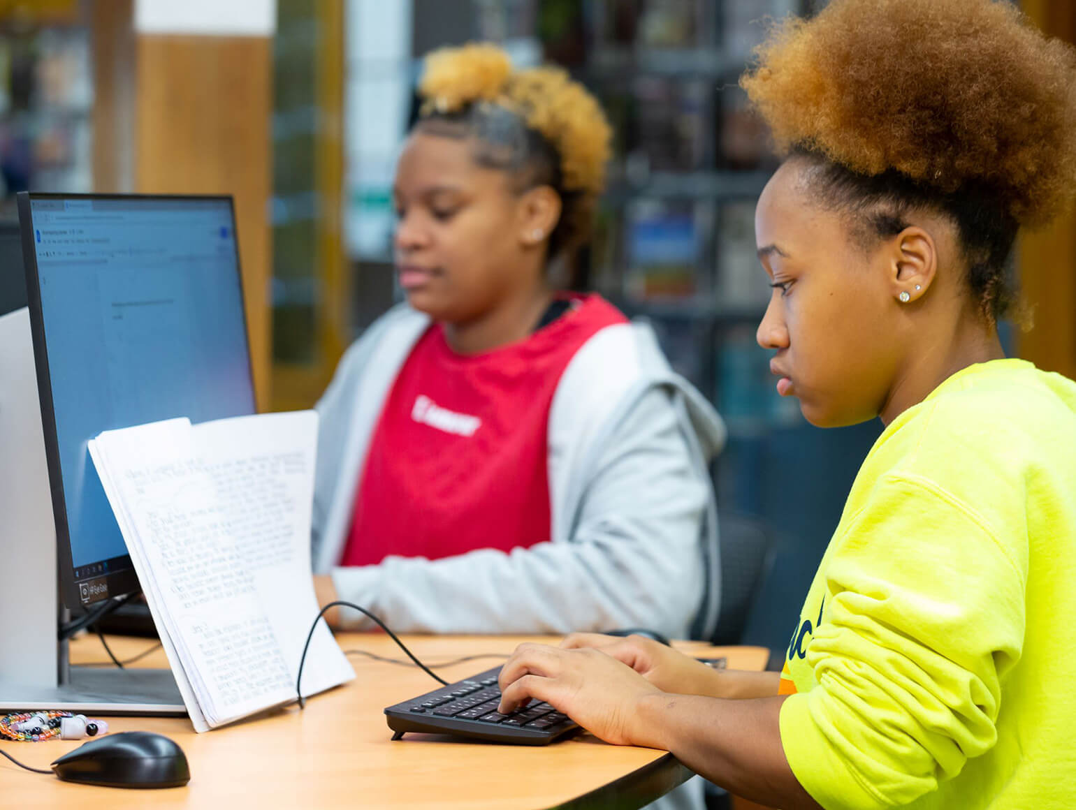 Two women using computers on campus.