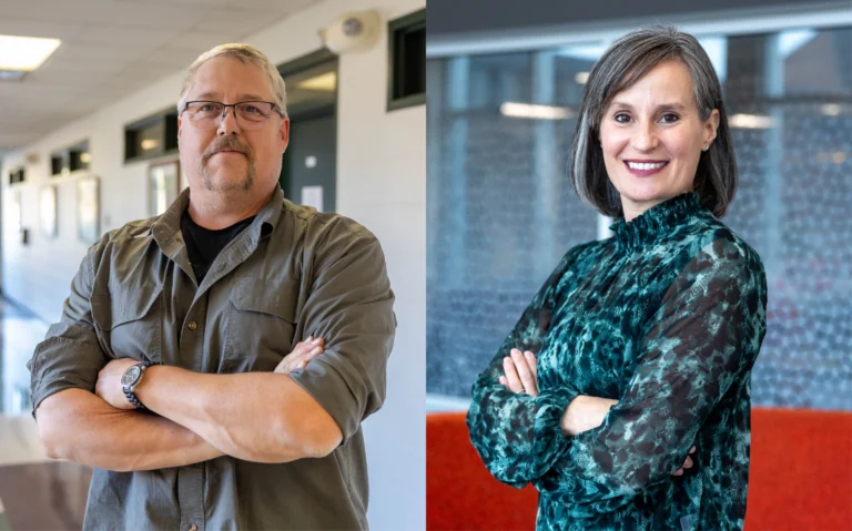 male with mustache and glasses and a dark gray shirt with arms crossed smiling, woman with gray and white hair smiling with arms crossed wearing a teal and black dotted shirt