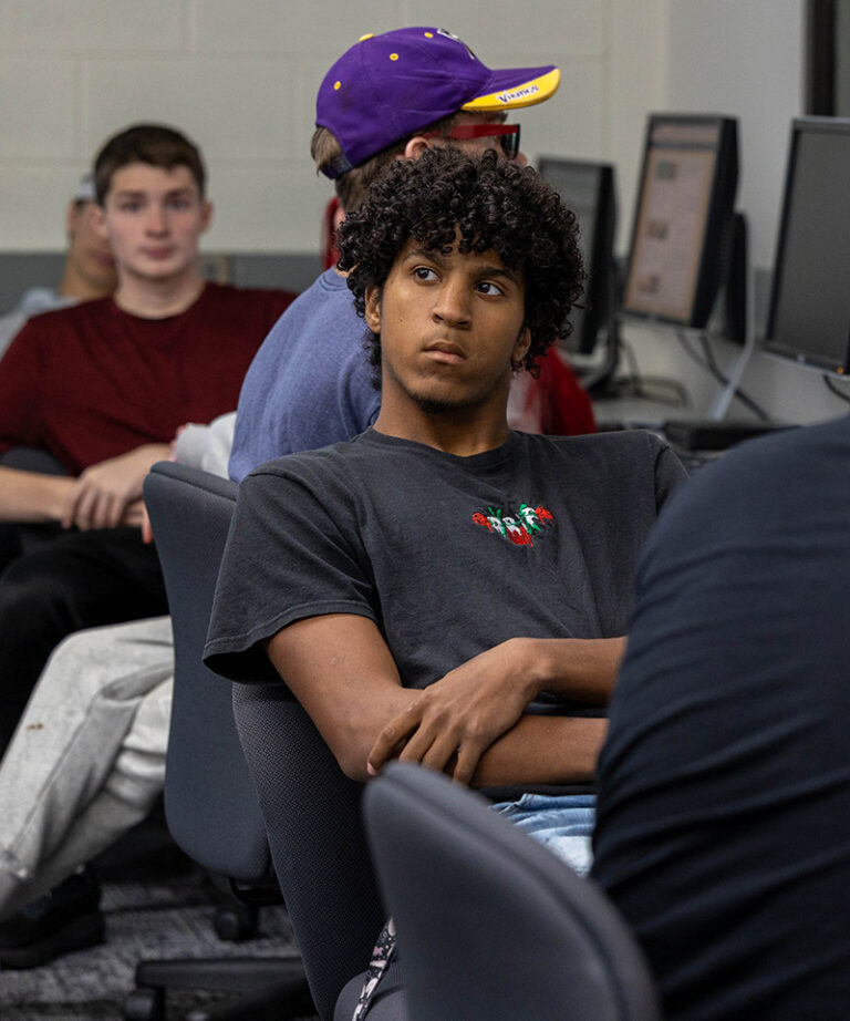 male african american student with curly hair sitting at a computer looking at the professor