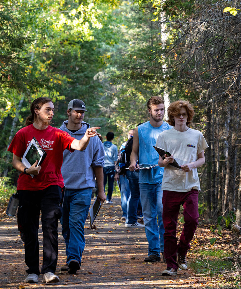 four male students outside with notebooks