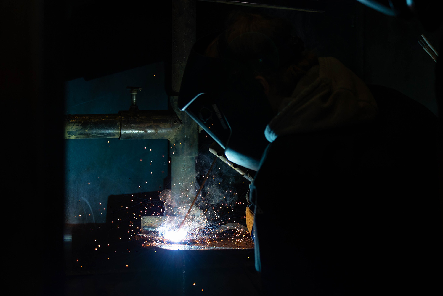student with welding mask on welding with sparks flying